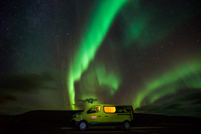 Green campervan with northern lights in the background