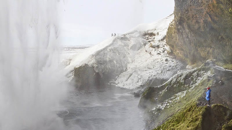 Woman standing by Seljalandsfoss waterfall