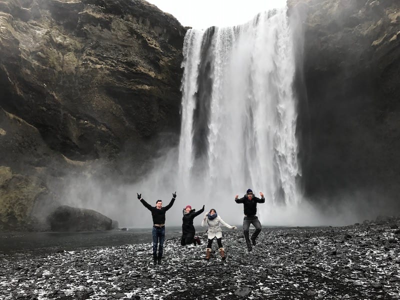 4 people jumping in front of Skogafoss waterfall