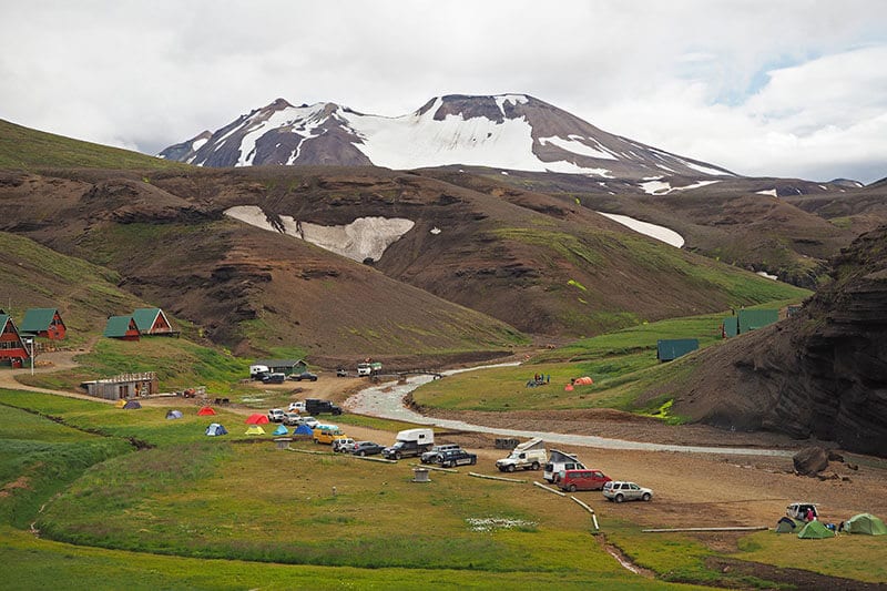 A group of cars parked in a campsite at the foot of a mountain