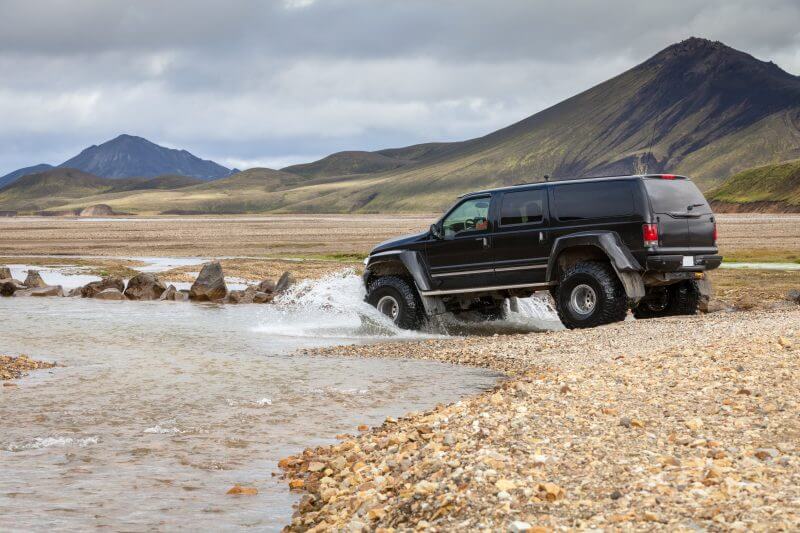 A black truck driving through a river