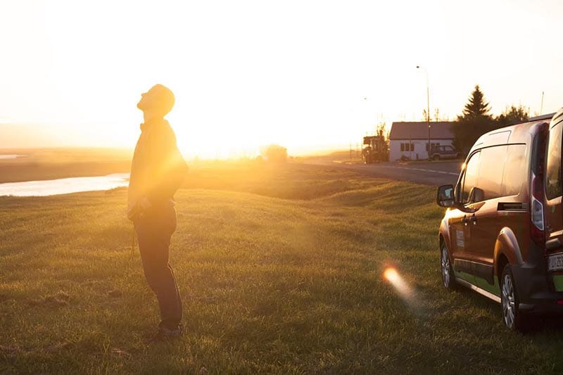 A man standing next to a campervan during sunset