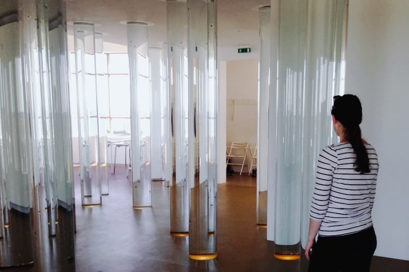 A young woman looking at a room with of glass pillars filled with water