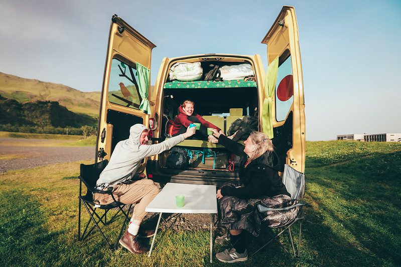 people toasting next to a yellow campervan