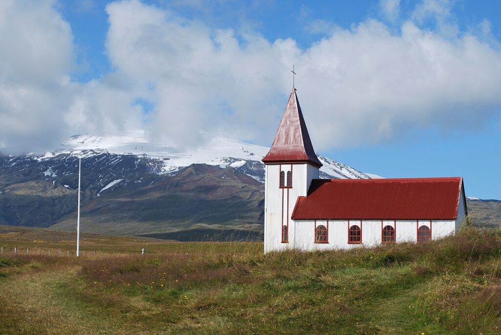 White church with red roof at the foot of Snafellsjokull glacier in Hellnar