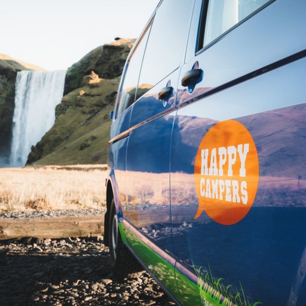 A Happy Camper campervan by Skogafoss waterfall in South Iceland