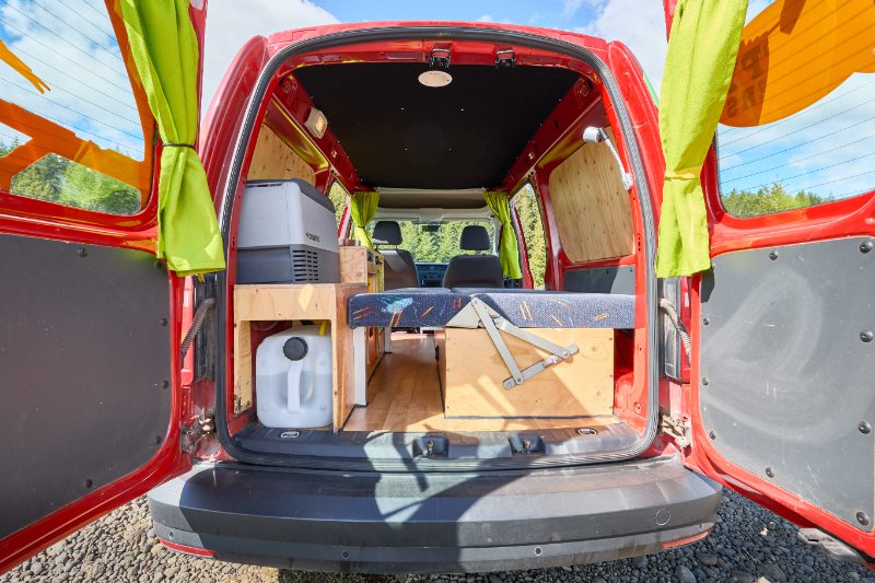 Rear view of the Happy 1 EX AUTO campervan rental in Iceland, showing a foldable bed, kitchenette, and compact storage—perfect for efficient and comfortable vanlife travel.