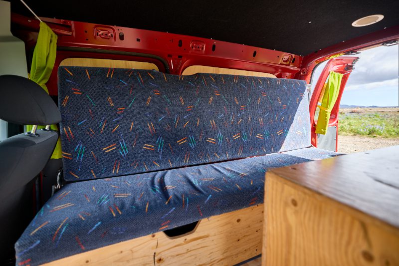 Comfortable foldable bench seat inside a camping van rental in Iceland, designed for sleeping and lounging during road trips.