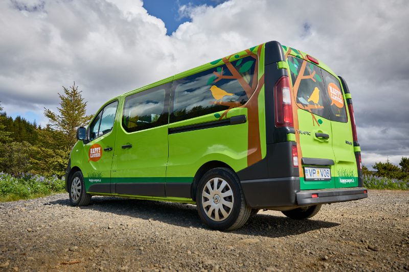 Rear side view of the Happy 2 EX campervan rental in Iceland, showcasing its vibrant green exterior, custom bird design, and spacious layout—ideal for flexible and scenic Icelandic road trips.